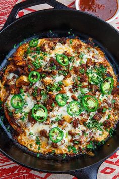 a pizza in a skillet on a table with sauces and condiments