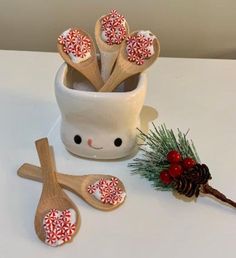 wooden spoons are sitting next to a cup with candy canes in it and a pine cone on the side