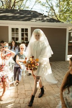 a woman is walking down the street wearing a wedding dress