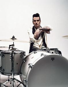 a man is playing drums in front of a drum set with one hand on his hip