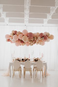 a bride and groom kissing under balloons over a table