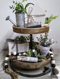 a three tiered tray with potted plants and books on it, along with other items