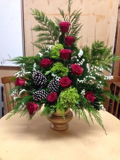 a vase filled with roses and greenery on top of a table