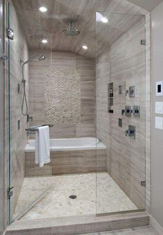 a walk in shower sitting next to a white bath tub under a sky light fixture