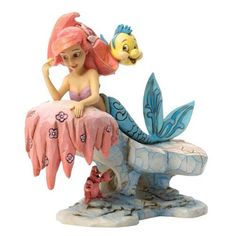 a figurine of a little mermaid sitting on top of a fish