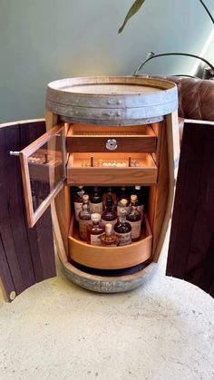 an old barrel is turned into a bar with liquor bottles in the bottom drawer and shelves