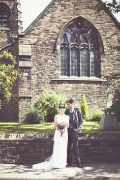 a bride and groom standing in front of a church