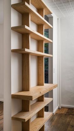 an empty room with wooden shelves on the wall and hard wood flooring in it