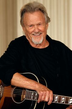 an older man holding a guitar in his hands