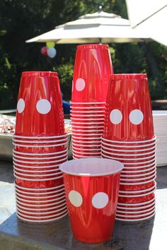 red cups with white polka dots on them are sitting in front of an outdoor table