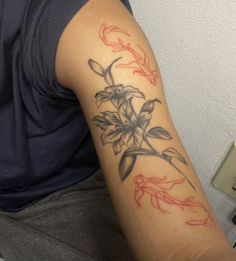 a man with a tattoo on his arm has a red and black flower in it