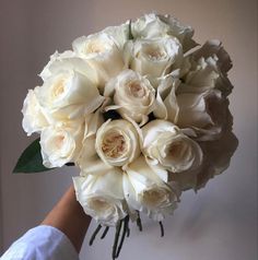 a bouquet of white roses in someone's hand