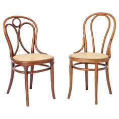 a pair of wooden chairs with wicker seats