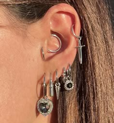 a close up of a person wearing ear rings and piercings with cross on them