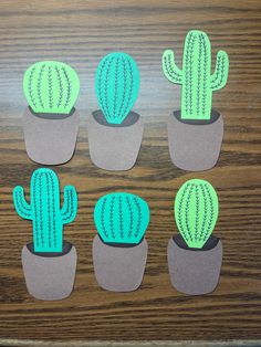 paper cactus cut outs sitting on top of a wooden table