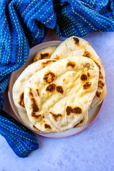 three flat breads on a plate with blue cloth