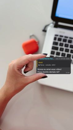 a woman is holding up her cell phone next to a laptop