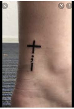 a cross tattoo on the foot of a person with no shoes in front of it