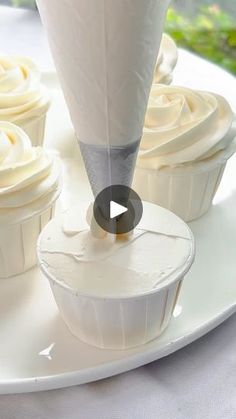 cupcakes being frosted with icing on a white plate