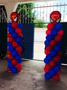 two red and blue balloons in the shape of spiderman's heads are standing next to each other