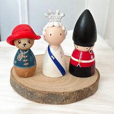 three small figurines are sitting on a wood slice