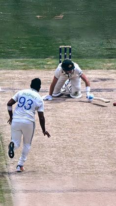 two men in white uniforms playing a game of cricket