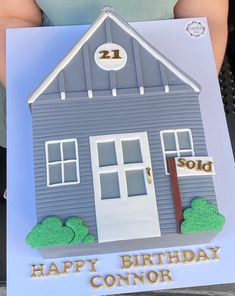 a person holding up a birthday card with a house on it