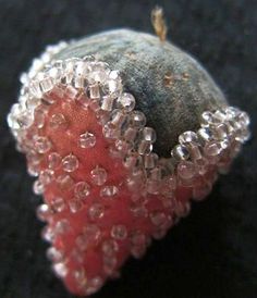 a piece of fruit with beads on it sitting on a black surface next to a rock