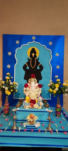 there is a blue table with flowers and an elephant statue on it, surrounded by other decorations