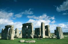 the stonehenge monument in england is surrounded by green grass and blue skies with fluffy clouds