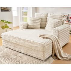 a white couch with pillows on top of it in front of a rug and window