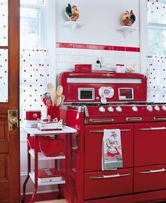 a red stove top oven sitting inside of a kitchen