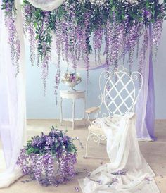 purple flowers are hanging from the ceiling in a room with white furniture and drapes