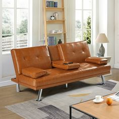 a brown leather couch sitting on top of a hard wood floor next to a coffee table