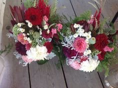 two vases filled with flowers sitting on top of a wooden table next to each other