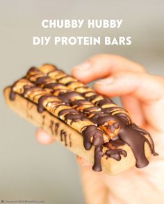 a person holding a chocolate covered hot dog in their hand with the words chubby hubby diy protein bars on it