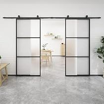 an empty room with white walls and black glass doors that lead into the dining area