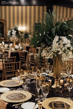 the table is set with gold and black plates, place settings, and centerpieces