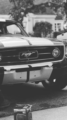 a black and white photo of a car parked on the side of the road with its hood up