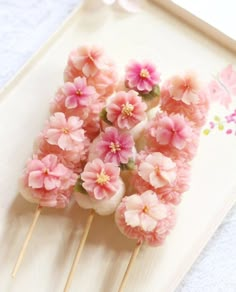 some pink flowers are sitting on top of toothpicks