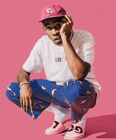 a man sitting on top of a pink floor next to a pair of tennis shoes