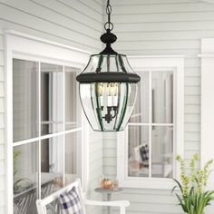 a lantern hanging from the ceiling in front of a porch with chairs and potted plant