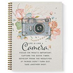 a spiral notebook with an image of a camera and flowers on the cover, which reads life is like cameras focus on what's important capture