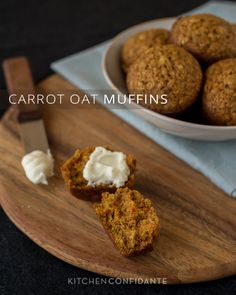 carrot muffins on a wooden cutting board next to a bowl of whipped cream