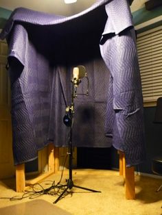 a photo studio setup with lights and lighting equipment in the foreground, behind it is a large purple cloth draped over a wooden stand