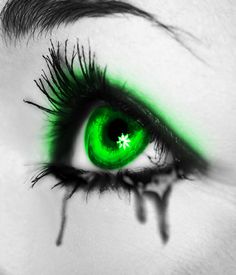 an eye with green eyeshade and long lashes is seen in this black and white photo