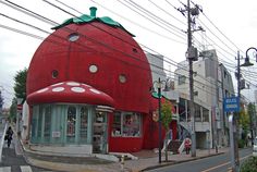 a giant strawberry shaped building on the corner of a street