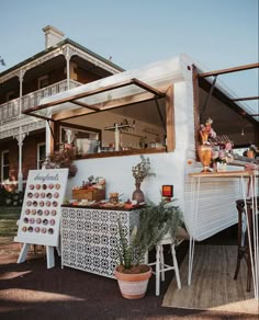 a food truck parked in front of a house with potted plants on the outside