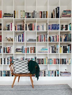 a chair sitting in front of a book shelf filled with books