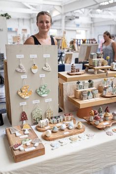 a woman standing next to a table filled with lots of different items on it's sides